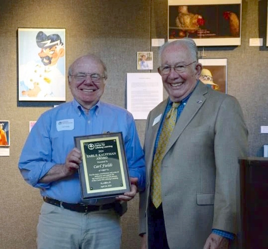 Carl Fields displays his 2024 Kauffman award while presenter Jim Tisaranni looks on.